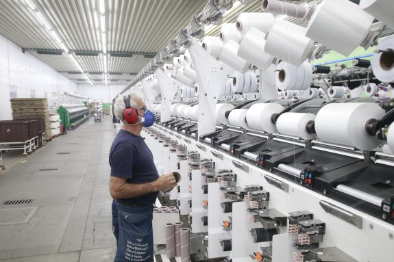 producción textil - Trabajador trabajando en una industria de producción textil.