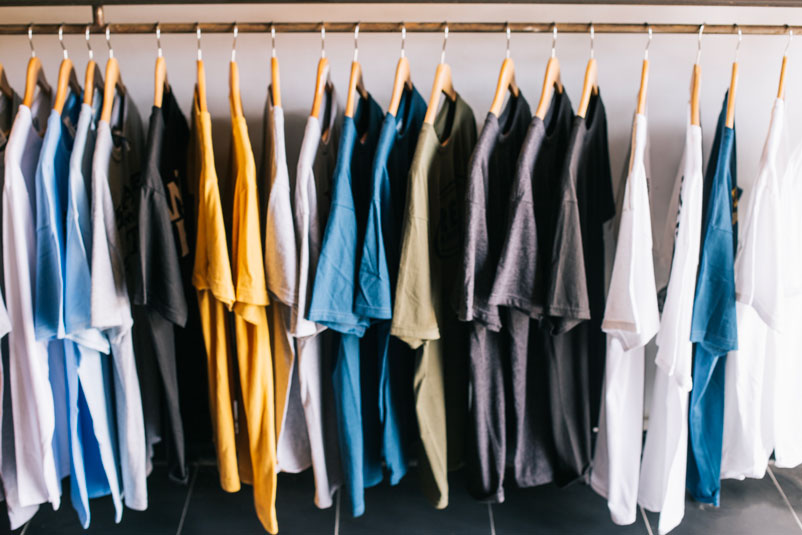 Las camisetas recién producidas con materias primas de alta calidad colgadas en un estante son el resultado de la constante modernización de la industria textil. 